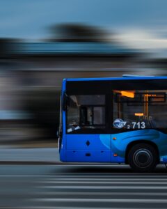 a blue bus driving down a street next to a tall building